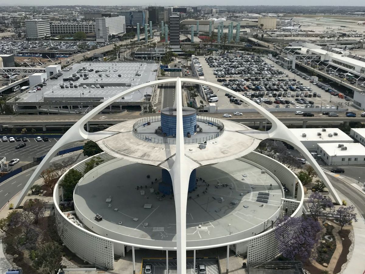 This image shows the Theme Building at Los Angeles International Airport (LAX), a distinctive structure with futuristic design and white arches.