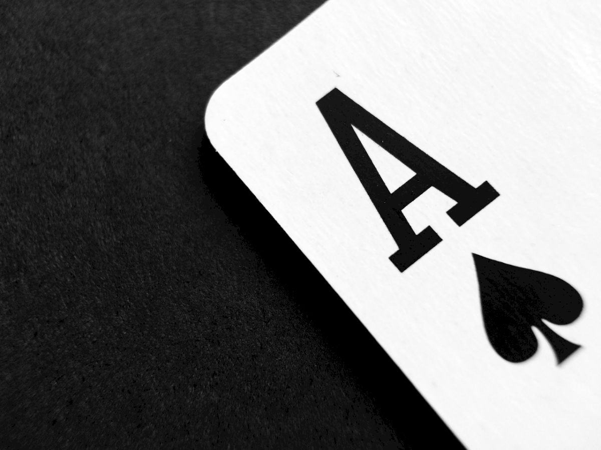 The image shows a close-up of a playing card, specifically an Ace of Spades, against a black background.